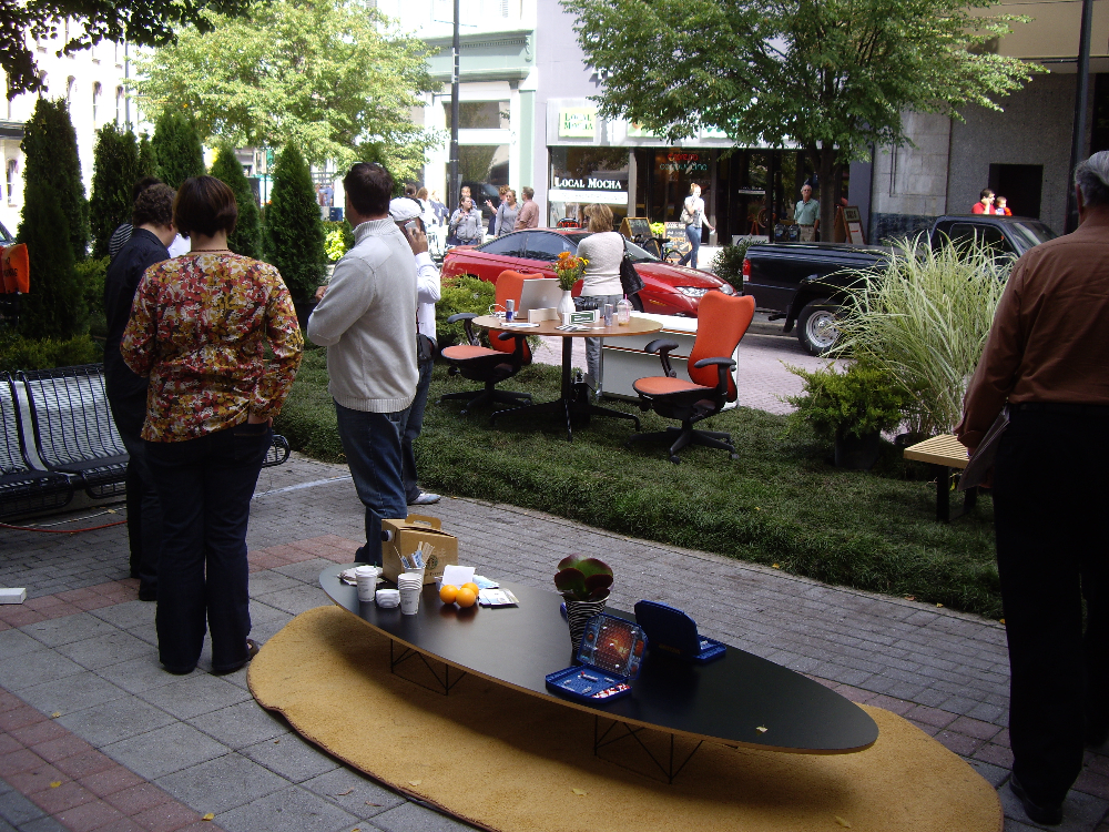 People on a sidewalk by a table with games and coffee
